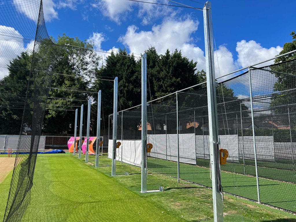 A side view of a cricket training and practising facility setup using nets.