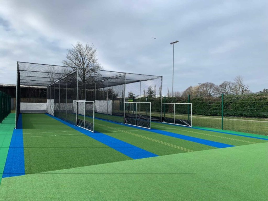 A zoomed-out view of a professional cricket training practice net facility.